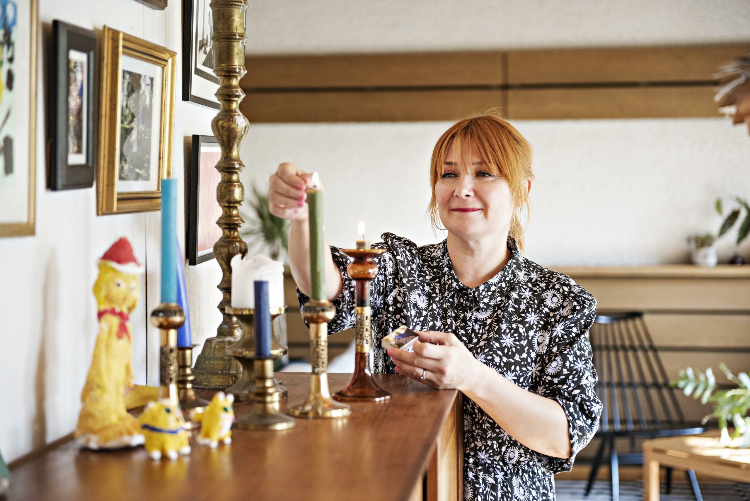 Muusikko Irina sytyttää lipaston päällä olevia kynttilöitä.